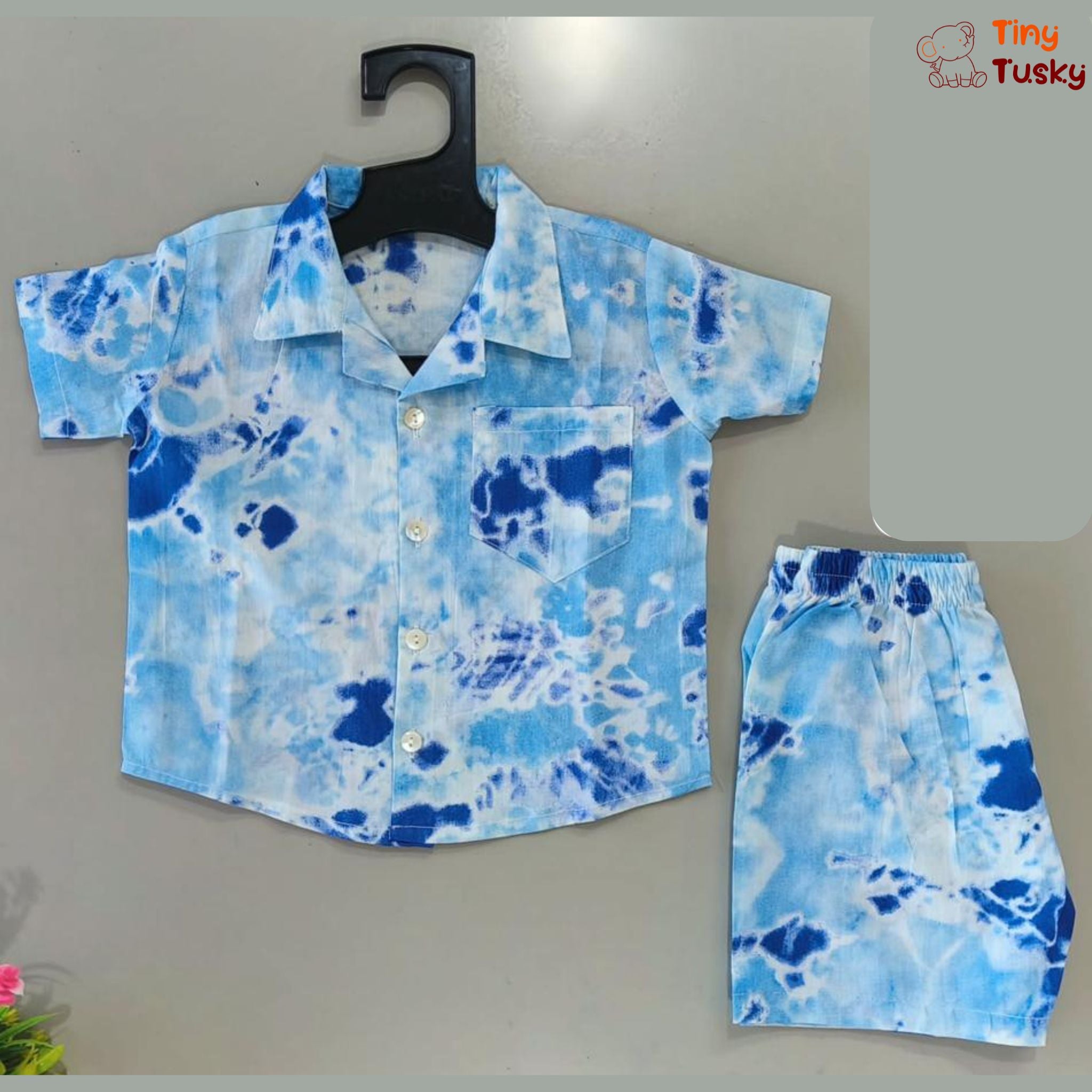 Catch some summer waves in style with the Tiny Tusky Kids' Beach Vibes Tie-Dye Co-Ord Set! This playful set is perfect for all your little adventurer's summer fun, from splashing at the beach to brunching in bohemian style.  Made from cool and comfortable 100% cotton, the tie-dye print in a vibrant blue color adds a touch of beachy flair to any occasion. The relaxed-fit shirt and shorts allow for easy movement and carefree fun, making it the perfect outfit for a day of summer adventures.